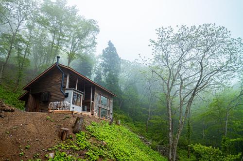a small house on a hill in the woods at 野尻湖の絶景を楽しむ、貸切サウナ付き一軒家 Anoie（あの家） in Shinano