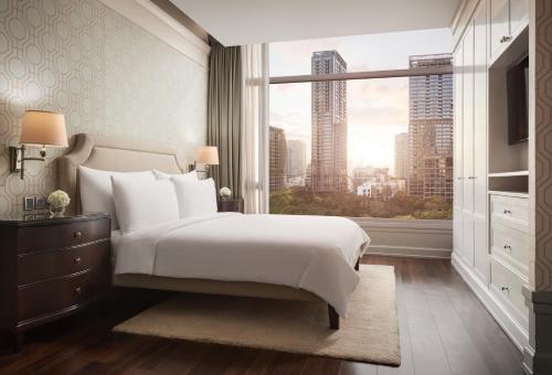 a bedroom with a large bed and a large window at Oriental Residence Bangkok in Bangkok