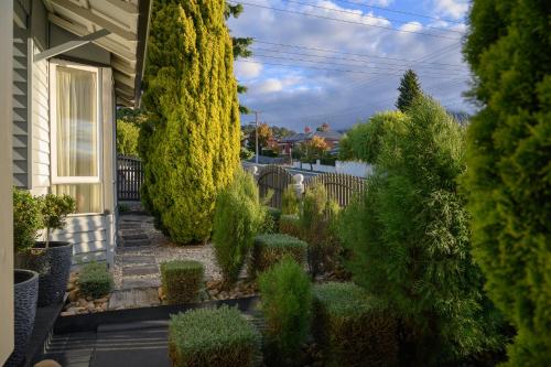 a garden with trees and bushes in front of a house at Bakers Retreat in Hobart