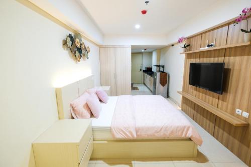 Un pequeño dormitorio con una cama y un televisor. en Warhol Residence at Louise Kienne Simpang Lima Semarang, en Semarang