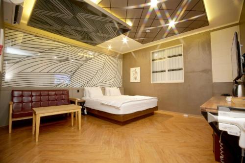 a bedroom with a bed and a bench in a room at Palace Hotel in Ulsan