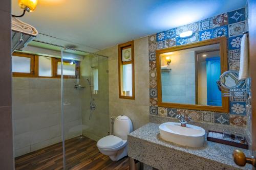 ein Badezimmer mit einem Waschbecken, einem WC und einem Spiegel in der Unterkunft Fragrant Nature Backwater Resort & Ayurveda Spa Kollam in Kollam
