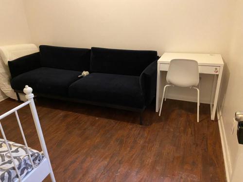 トロントにあるBUDGET Triple Room with En Suite Bathroom 36Aのデスクと椅子付きの客室で、黒いソファが備わります。