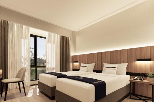 a bedroom with two beds and a desk and a window at Fieris Hotel & Convention Kertajati in Dawuhan