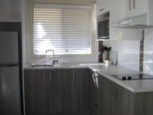 a white kitchen with a sink and a window at Reflections Eden - Holiday Park in Eden