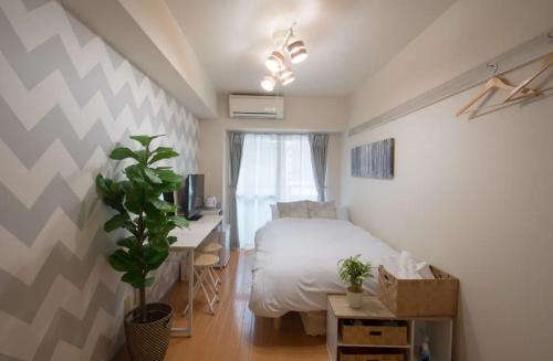 1 dormitorio con 1 cama y escritorio con ordenador en Hirose inn F+ en Hiroshima