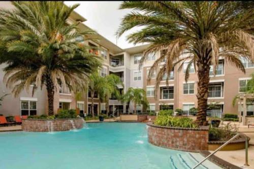 a swimming pool with palm trees in front of a building at Heart of NRG and Medical Center in Houston