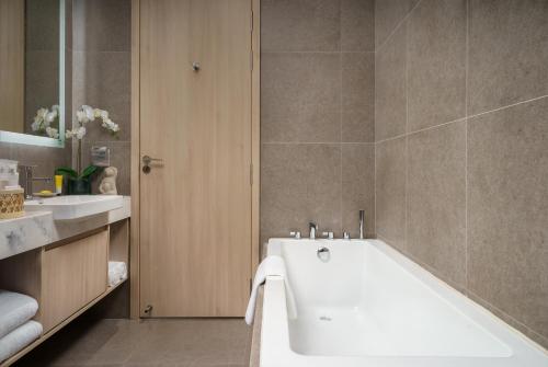 a bathroom with a white tub and a sink at Capri by Fraser, Phnom Penh in Phnom Penh