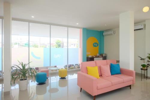 a living room with a pink couch and colorful chairs at Sans Hotel Aurum Semarang in Semarang