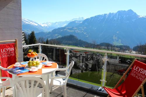 a table and chairs on a balcony with mountains at Résidences du Chamossaire in Leysin