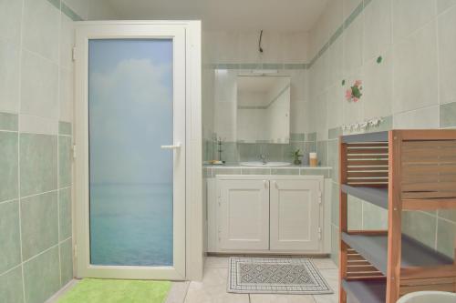 ein Bad mit einer Tür, die zu einem Waschbecken führt in der Unterkunft AU MEUBLE DURANTAS in Petite Île