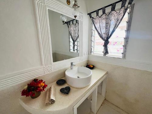 a white bathroom with a sink and a mirror at Beba.Beach.House in Watamu