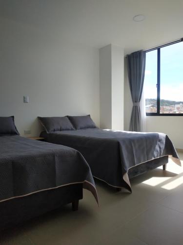 - une chambre avec 2 lits et une grande fenêtre dans l'établissement Apartamento Zipa 301, à Paipa