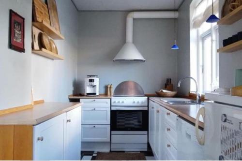 uma cozinha com armários brancos e um forno com placa de fogão em Skønt feriehus midt i Marstal. em Marstal