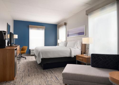 a hotel room with a bed and a couch at Holiday Inn Express and Suites New Orleans Airport, an IHG Hotel in Saint Rose