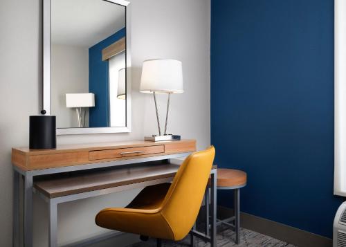 a desk with a mirror and a yellow chair at Holiday Inn Express and Suites New Orleans Airport by IHG in Saint Rose