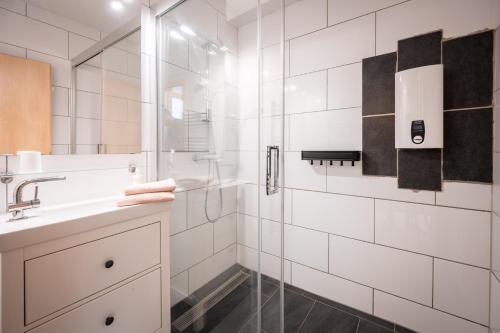 ein weißes Bad mit einer Dusche und einem Waschbecken in der Unterkunft MOOKI Lake Apartment Ossiacher See&Gerlitzen in Sattendorf