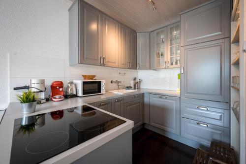 a kitchen with white cabinets and a microwave at Wohnung Seeblick in Sattendorf