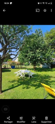 a picnic table in the grass next to a tree at A 15 mn ouest Caen in Noyers-Bocage