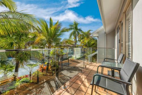 a balcony with a view of the ocean and palm trees at 7 Pelican Beach Resort in Noosaville