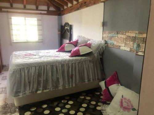 1 dormitorio con 1 cama con almohadas rosas y blancas en Linda cabaña con el mejor clima en Rionegro