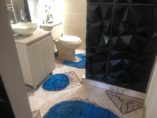 baño con aseo y 2 alfombras azules en Linda cabaña con el mejor clima en Rionegro