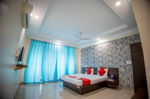 a bedroom with a bed with blue curtains and red pillows at Hotel Om Palace in Lonavala