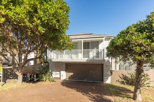 a white house with a garage in front of it at Banksia in Blueys Beach
