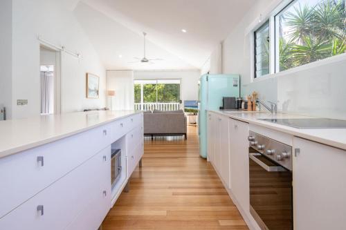 a kitchen with white cabinets and a blue refrigerator at Banksia in Blueys Beach