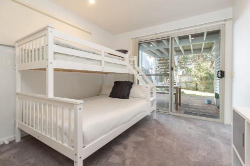 a white bedroom with a bunk bed and a window at Banksia in Blueys Beach