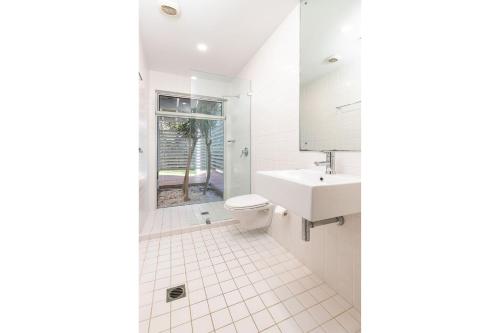 a white bathroom with a sink and a toilet at Banksia in Blueys Beach