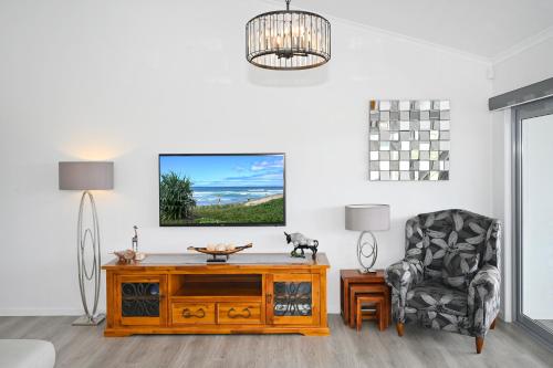 a living room with a tv and a chair at Stunning, Beachfront Dream Home - ZA3 in Buddina