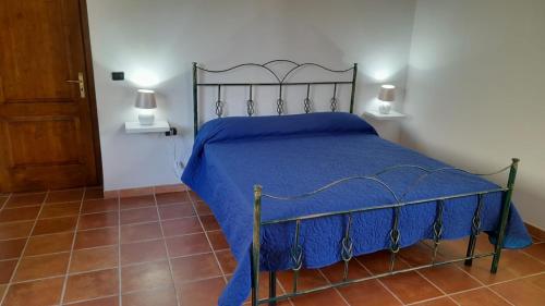 una camera da letto con un letto con copriletto blu e 2 lampade di Villa Aurora a Montegiordano