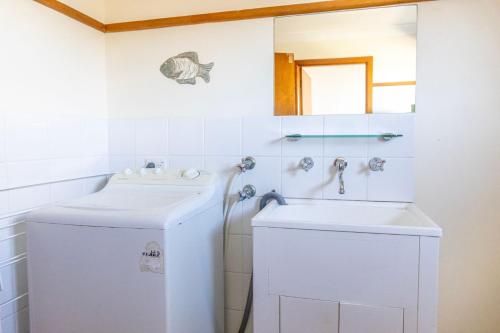 y baño con lavabo y lavadora. en Berrara Cove Beach House en Berrara