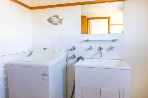 a bathroom with a sink and a washing machine at Berrara Cove Beach House in Berrara