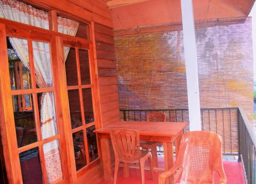 um alpendre com uma mesa de madeira e cadeiras numa varanda em Green cottage Ella em Ella