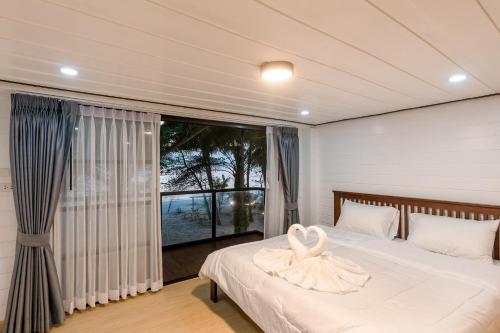 sypialnia z łóżkiem i dużym oknem w obiekcie Beach House Pool Villa w mieście Nakhon Si Thammarat