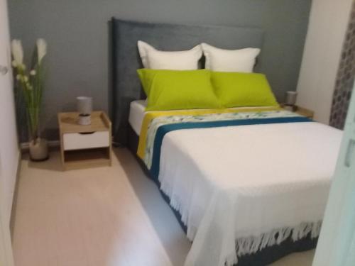 ein Schlafzimmer mit einem Bett mit grünen Kissen und einem Tisch in der Unterkunft AU MEUBLE DURANTAS in Petite Île