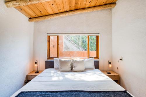 a bedroom with a bed with two lamps and a window at Beautiful & Warm Cabin with Lakeview 3BR 2 5BA in Valle de Bravo