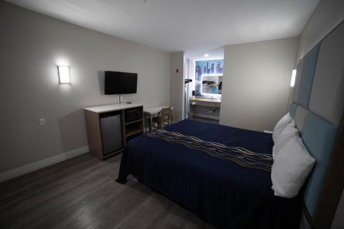 a hotel room with a bed and a television at Mid City Inn & Suites Pico Rivera in Pico Rivera