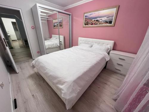 een slaapkamer met een wit bed en een roze muur bij EBI Apartment in Cluj-Napoca