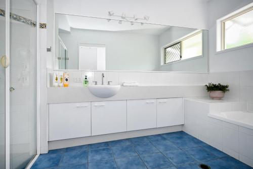 a white bathroom with a sink and a mirror at Stunning Mooloolaba Waterfront Home -10 guests ZB1 in Mooloolaba