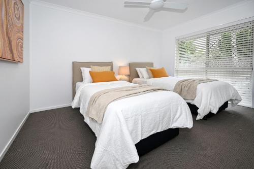 a bedroom with two beds with white and orange pillows at Stunning Mooloolaba Waterfront Home -10 guests ZB1 in Mooloolaba