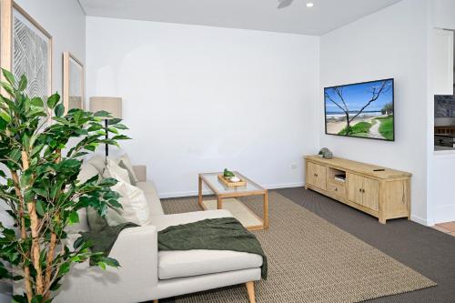 a living room with a couch and a tv on a wall at Stunning Mooloolaba Waterfront Home -10 guests ZB1 in Mooloolaba