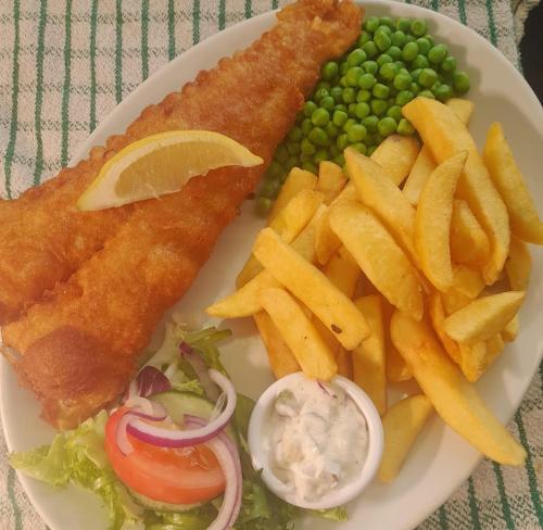a plate of food with fish and chips and peas at The Queen Victoria in Snettisham