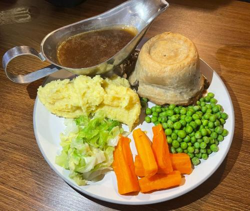 a plate of food with peas carrots and a sandwich at The Queen Victoria in Snettisham