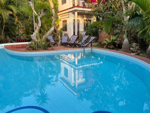 a swimming pool with chairs and a house in the background at Happy Family Guesthouse in Vĩnh Long