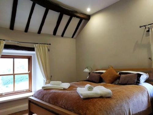 a bedroom with a large bed with two towels on it at Church Farm Cottage Fritchley in Crich