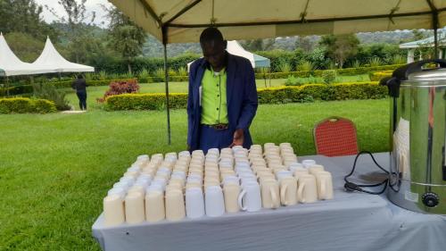 un hombre parado frente a una mesa de botellas de leche en HILLVIEW ECO-TOURISM RESORT, en Bungoma