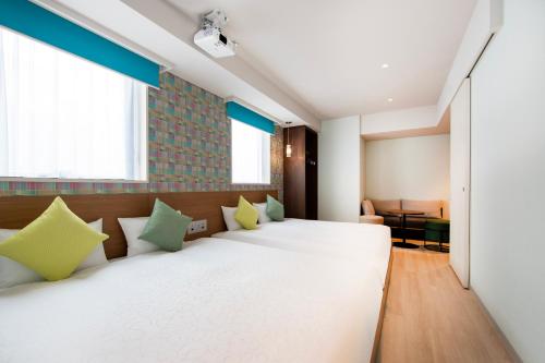 a bedroom with two beds with green and white pillows at karaksa hotel colors Tokyo Yaesu in Tokyo